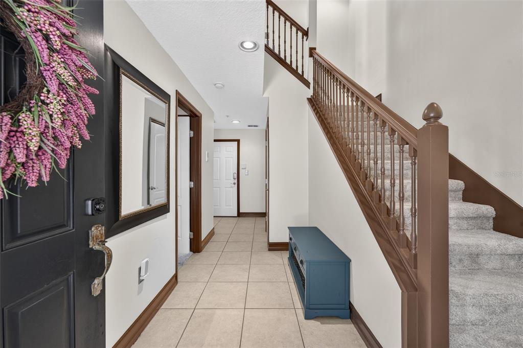 An entryway features a tiled floor, a carpeted staircase with wooden railings, and a blue bench — 4908 SAN MARINO CIRCLE, LAKE MARY, FL