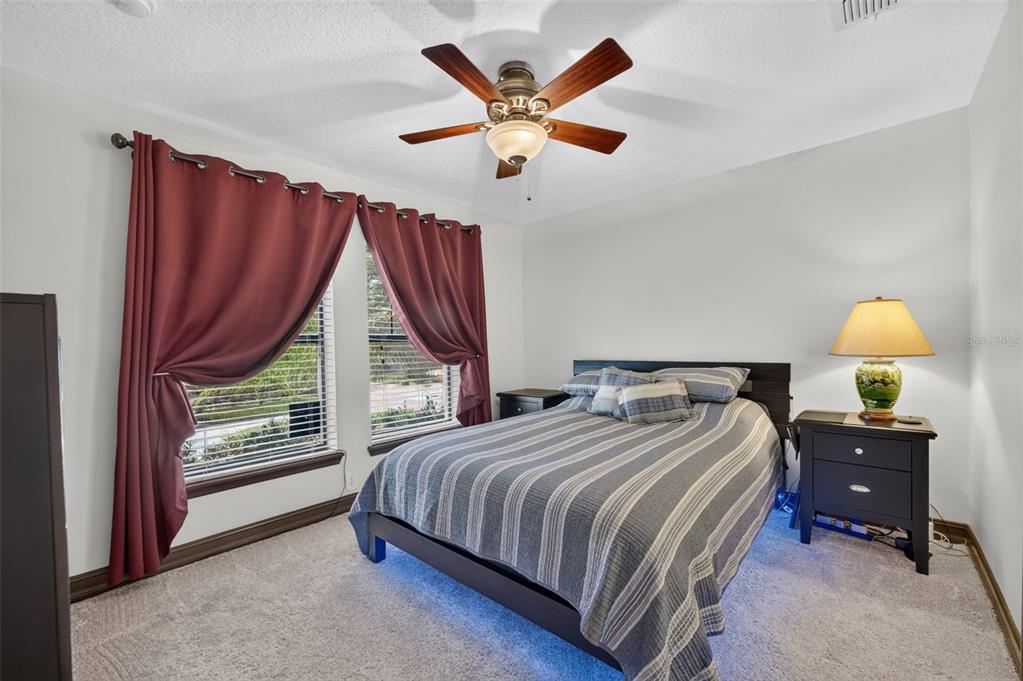 A bedroom features a bed with a striped comforter, dark wood furniture, and maroon curtains — 4908 SAN MARINO CIRCLE, LAKE MARY, FL