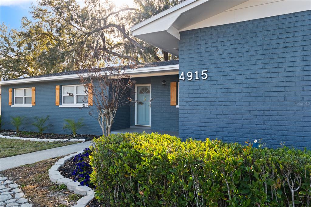 A blue brick house exterior features a light blue front door and wooden shutters — 4915 WHITEOAK DRIVE E, LAKELAND, FL