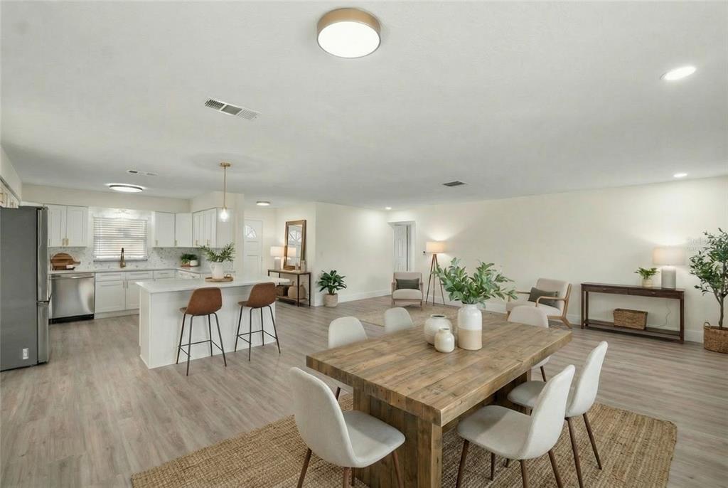 An open-concept kitchen and dining area features light wood flooring, white cabinetry, and a wooden table — 4915 WHITEOAK DRIVE E, LAKELAND, FL