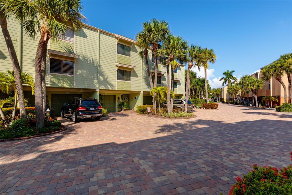 A wooden dock extends into a calm bay with a concrete walkway and distant buildings — 505 SANDY HOOK ROAD UNIT 505, TREASURE ISLAND, FL