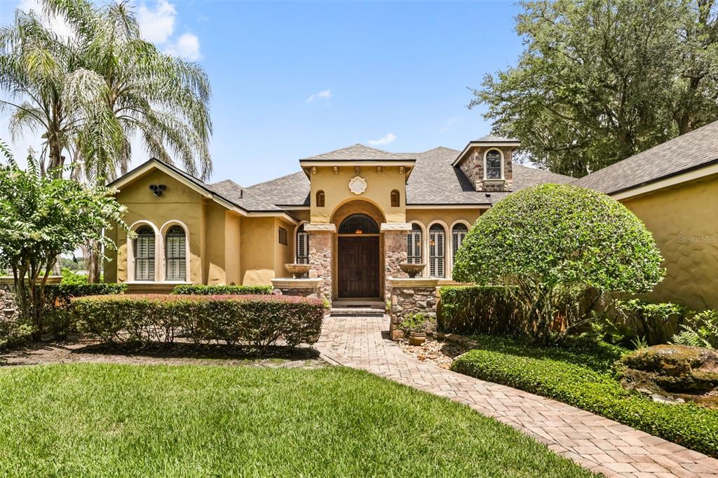 A single-story stucco house with a stone entryway, arched front door, and brick walkway — 863 CARDINAL POINTE COVE, SANFORD, FL