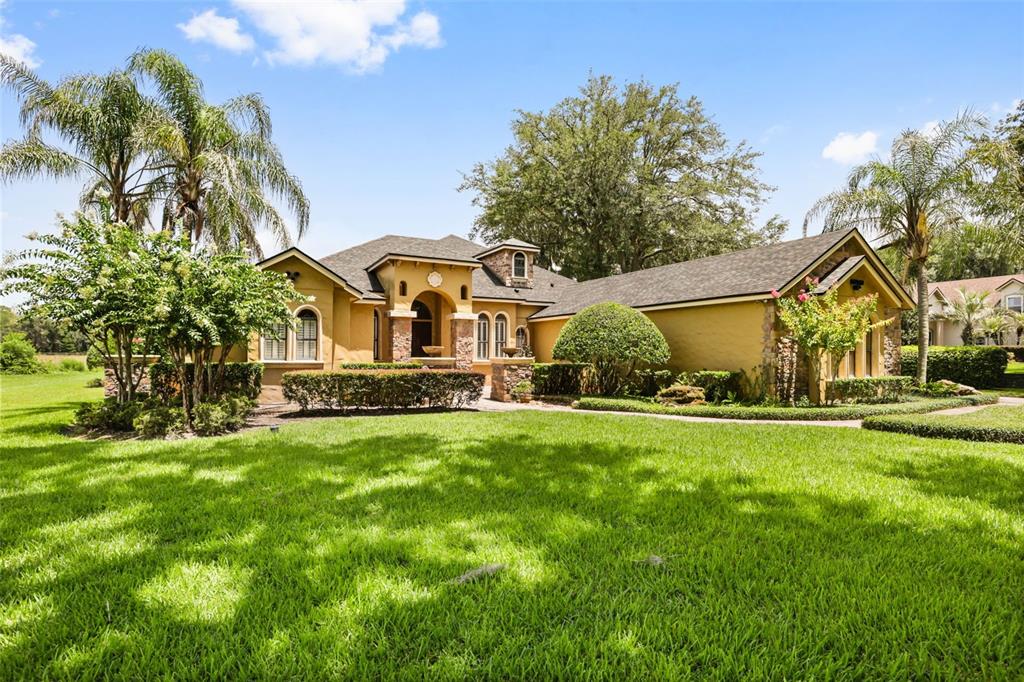A yellow stucco house with a stone entryway and a large green lawn — 863 CARDINAL POINTE COVE, SANFORD, FL