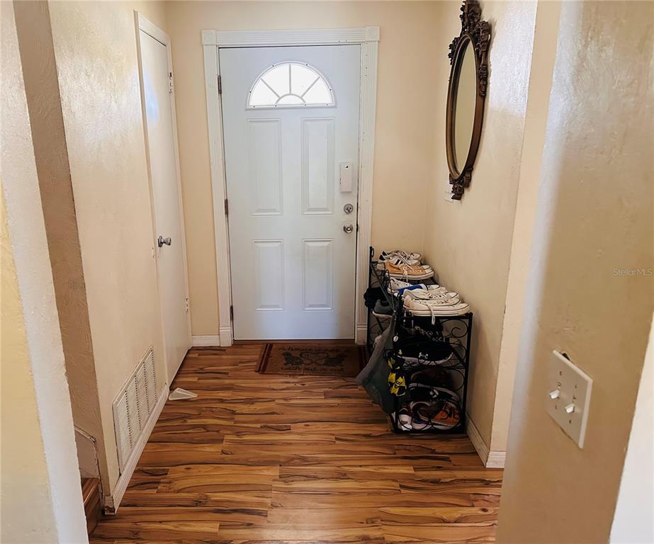 An entryway features wood-look flooring, a white front door, and a metal shoe rack — 1649 E SHANGRI LA DRIVE, DAYTONA BEACH, FL