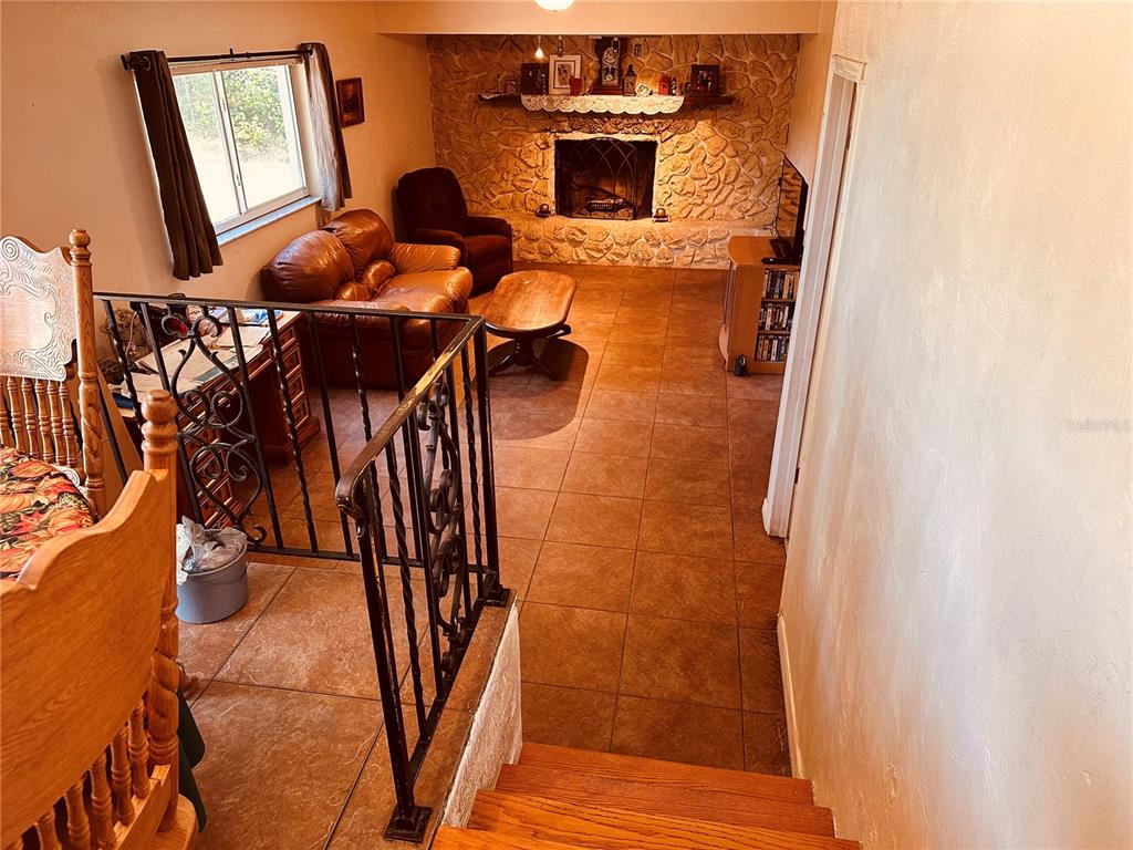 A sunken living room features a stone fireplace, tile flooring, and a wrought iron railing — 1649 E SHANGRI LA DRIVE, DAYTONA BEACH, FL