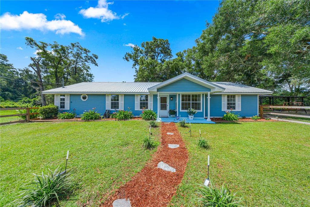 A blue single-story house with a metal roof and a stone path in the yard — 1890 NW 167TH PLACE, TRENTON, FL