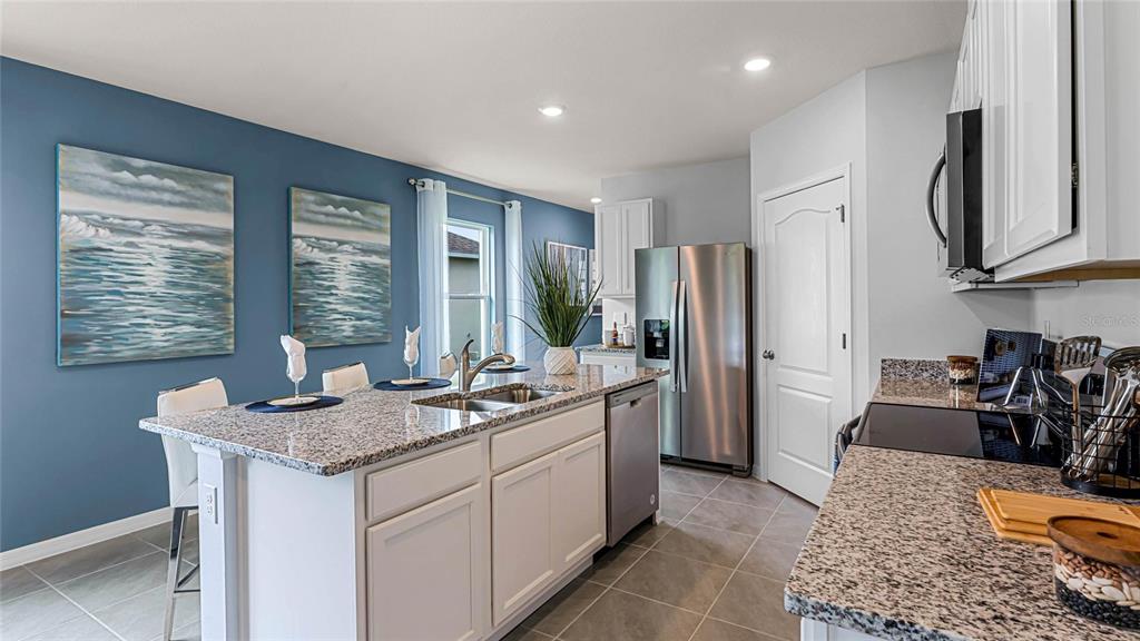 A kitchen features a granite-topped island, stainless steel appliances, and blue accent walls — 7080 FLINT CREEK DRIVE, LAND O LAKES, FL