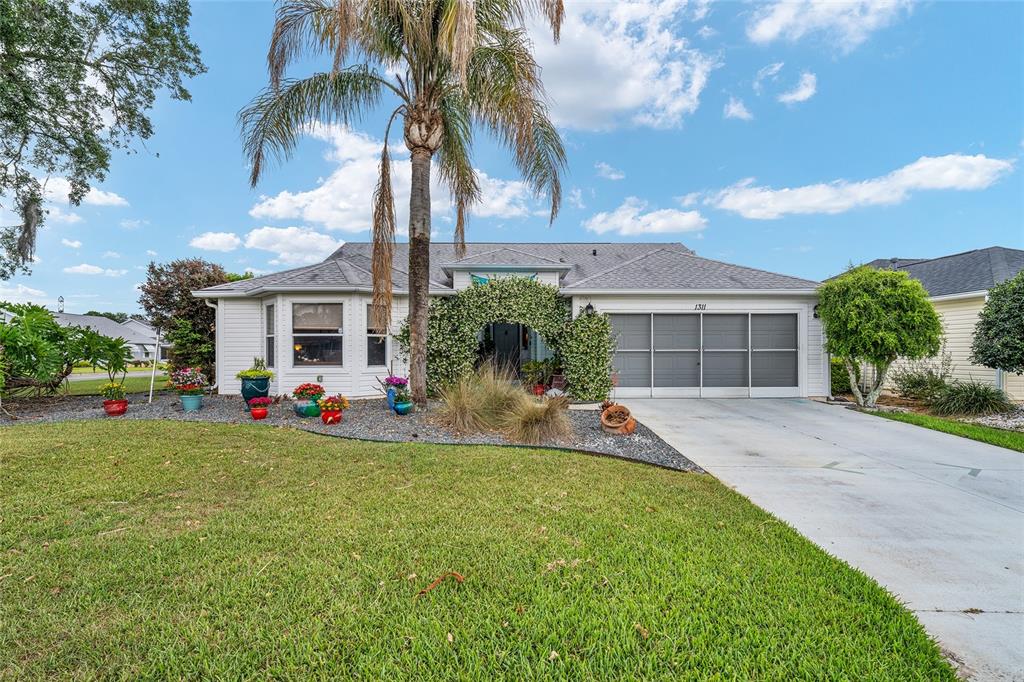 A single-story house with white siding, a gray roof, and a screened garage door — 1311 OPORTO DRIVE, THE VILLAGES, FL