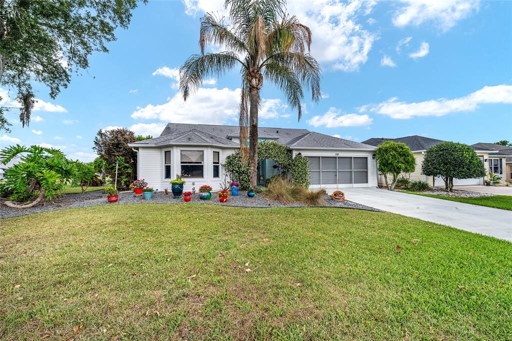 A single-story house with a palm tree, a front lawn, and a concrete driveway — 1311 OPORTO DRIVE, THE VILLAGES, FL