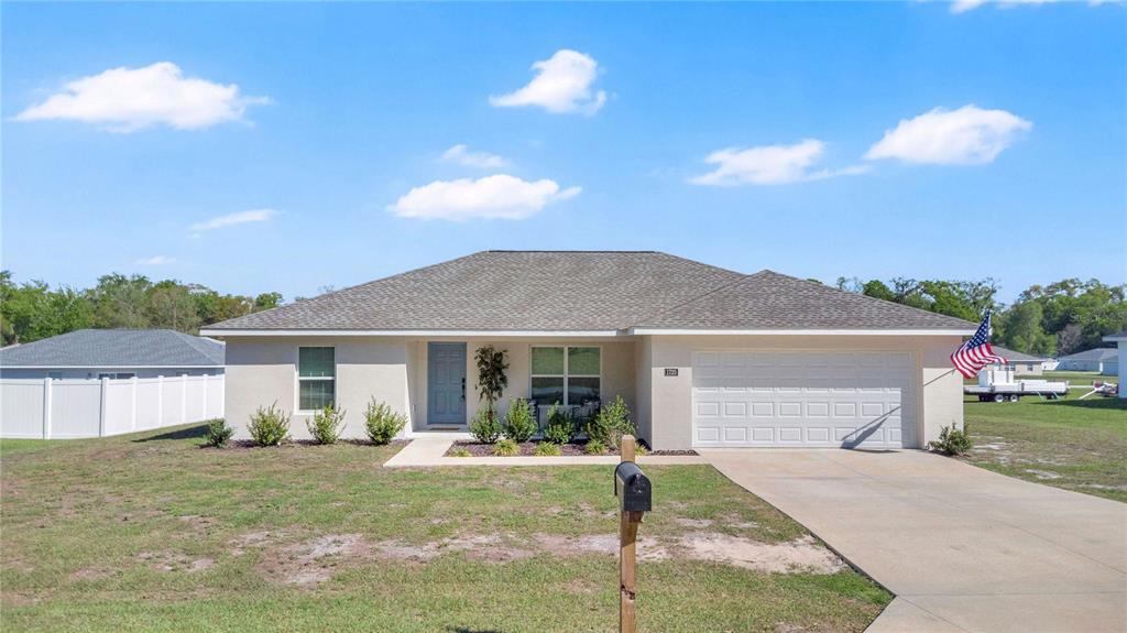 A single-story stucco house with a gray shingled roof and a two-car garage — 1725 NE 160TH PLACE, CITRA, FL