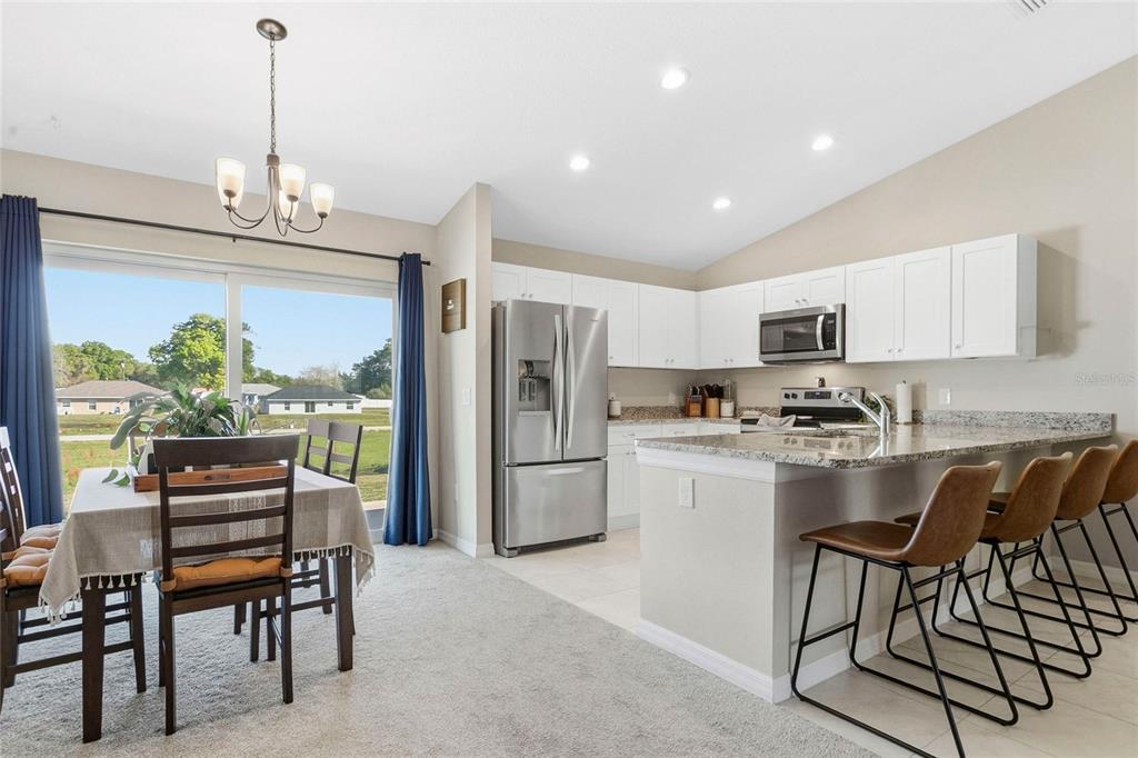 A kitchen with white cabinets and stainless steel appliances opens to a dining area — 1725 NE 160TH PLACE, CITRA, FL