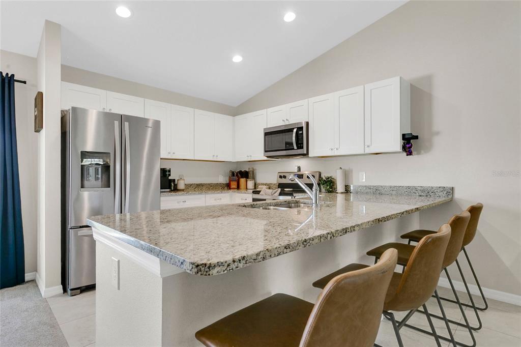 A kitchen features white cabinets, granite countertops, stainless steel appliances, and a breakfast bar — 1725 NE 160TH PLACE, CITRA, FL
