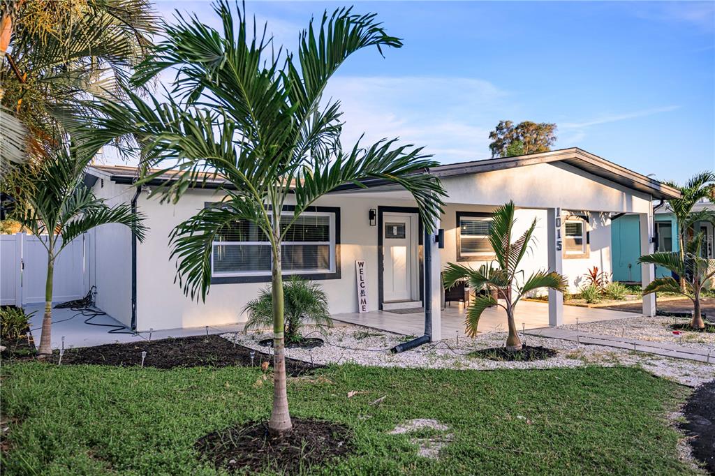A single-story white house features a covered front porch, palm trees, and a gravel yard — 1015 BOCA CIEGA ISLE DRIVE, ST PETE BEACH, FL