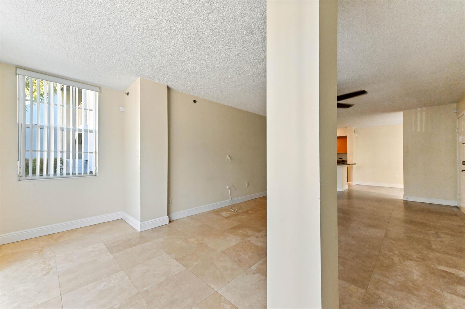 An empty room with beige tile floors, a textured ceiling, and a vertical window — 3237 Clint Moore Road # 107, Boca Raton FL 33496, BOCA RATON, FL