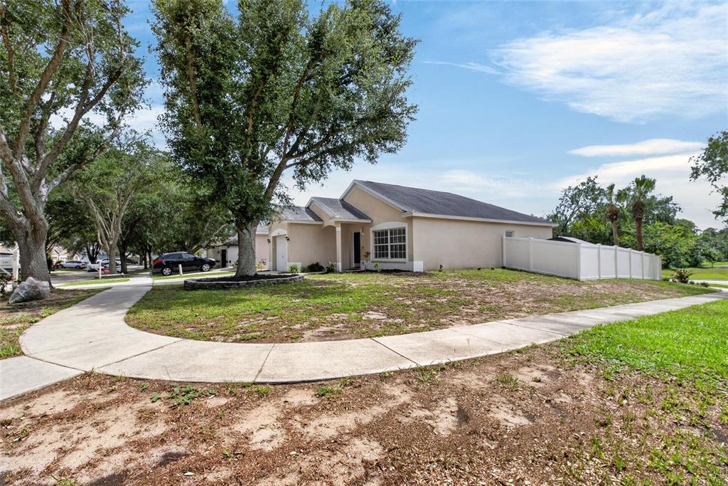 A single-story beige house with a white fence and a large tree in the yard — 346 SUMMER SAILS DRIVE, VALRICO, FL