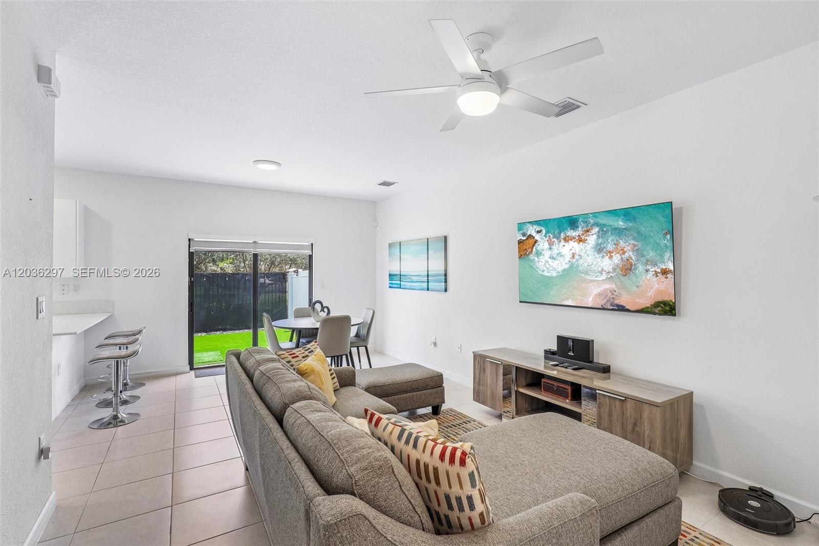 A living room features a grey sectional sofa, a wall-mounted television, and a dining area — 592 NW 203rd Ter, Miami Gardens FL 33169, MIAMI GARDENS, FL