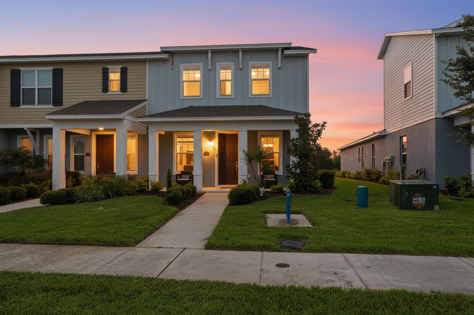 A two-story townhouse exterior features a covered front porch, light blue siding, and a lawn — 4997 Avalon Park Boulevard, FL 33545, FL