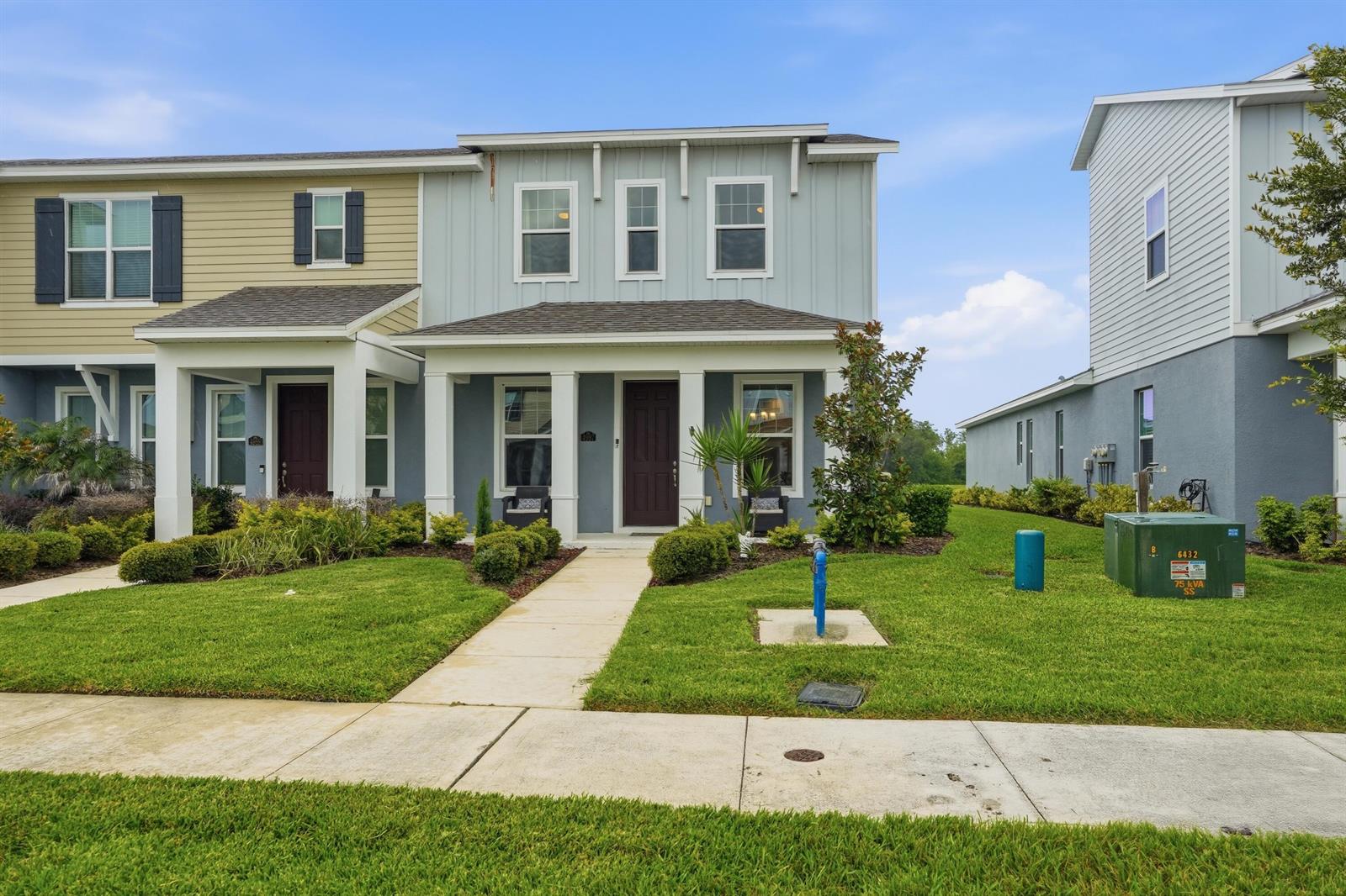 A two-story townhouse with a light blue exterior, a covered front porch, and a lawn — 4997 Avalon Park Boulevard, FL 33545, FL