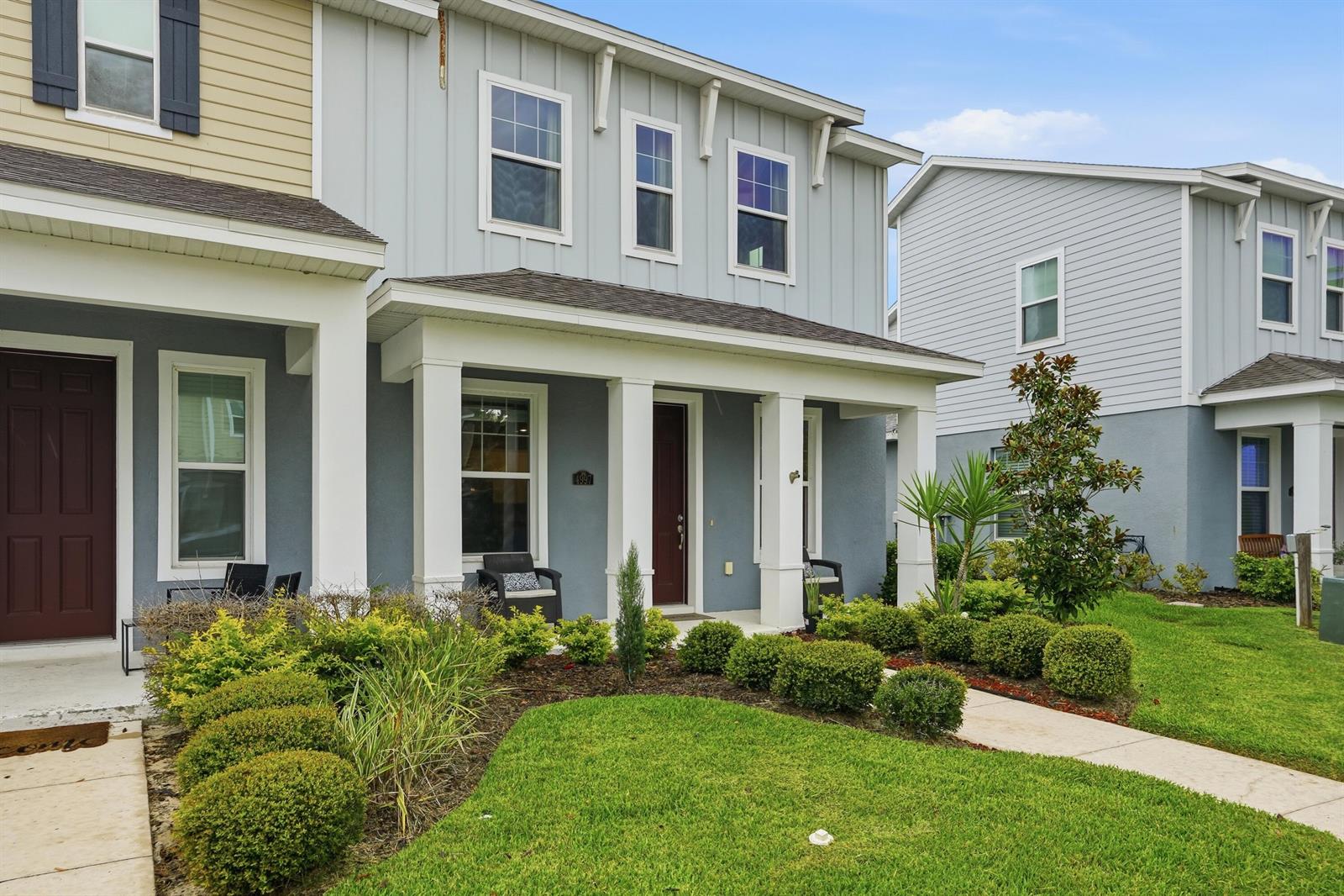A two-story house with a covered front porch, gray siding, and a landscaped front yard — 4997 Avalon Park Boulevard, FL 33545, FL