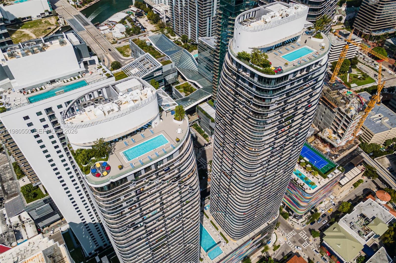 A swimming pool with lounge chairs sits on a terrace between two tall buildings — 55 SW 9th St # 1109, Miami FL 33130, MIAMI, FL