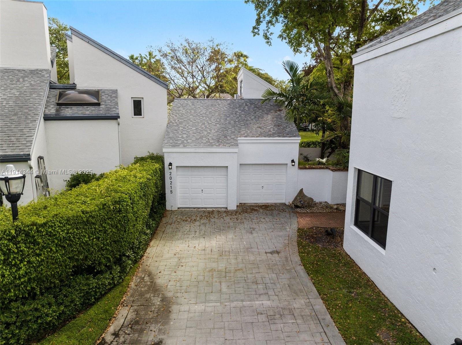 An exterior view shows a two-car garage with a paved driveway and white stucco walls — 20215 W Oak Haven Cir, Miami FL 33179, MIAMI, FL
