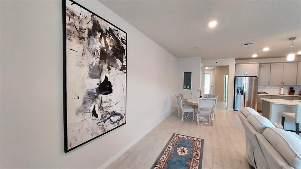 A living and dining area features light wood flooring, modern furniture, and a large abstract painting — 14169 LANIKAI BEACH DRIVE, ORLANDO, FL