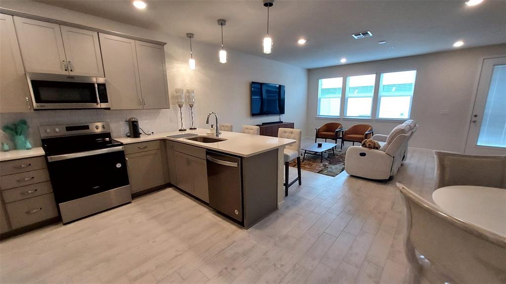 An open-concept kitchen features light gray cabinetry, stainless steel appliances, and a central island — 14169 LANIKAI BEACH DRIVE, ORLANDO, FL