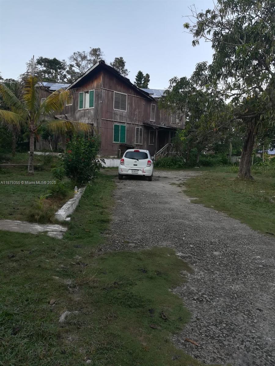 A two-story wooden house with a gravel driveway and a white car parked in front — 00 West end, Negril Jamaica, NA, NA