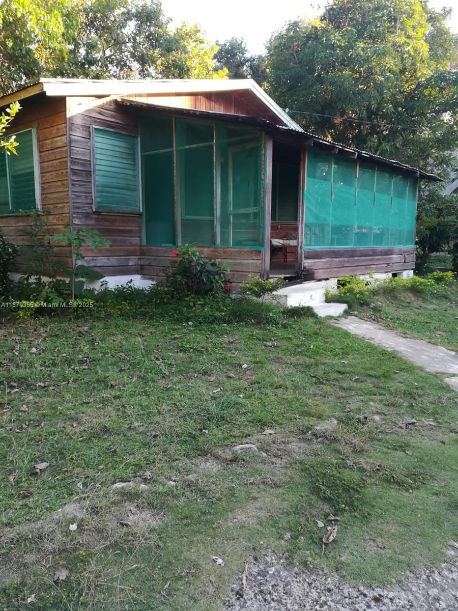 A wooden house with a screened-in porch stands on a grassy lot — 00 West end, Negril Jamaica, NA, NA