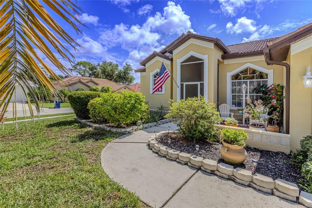 A patio area features two white chairs, potted plants, and a screen door entrance — 4092 HEARTHSTONE DRIVE, SARASOTA, FL