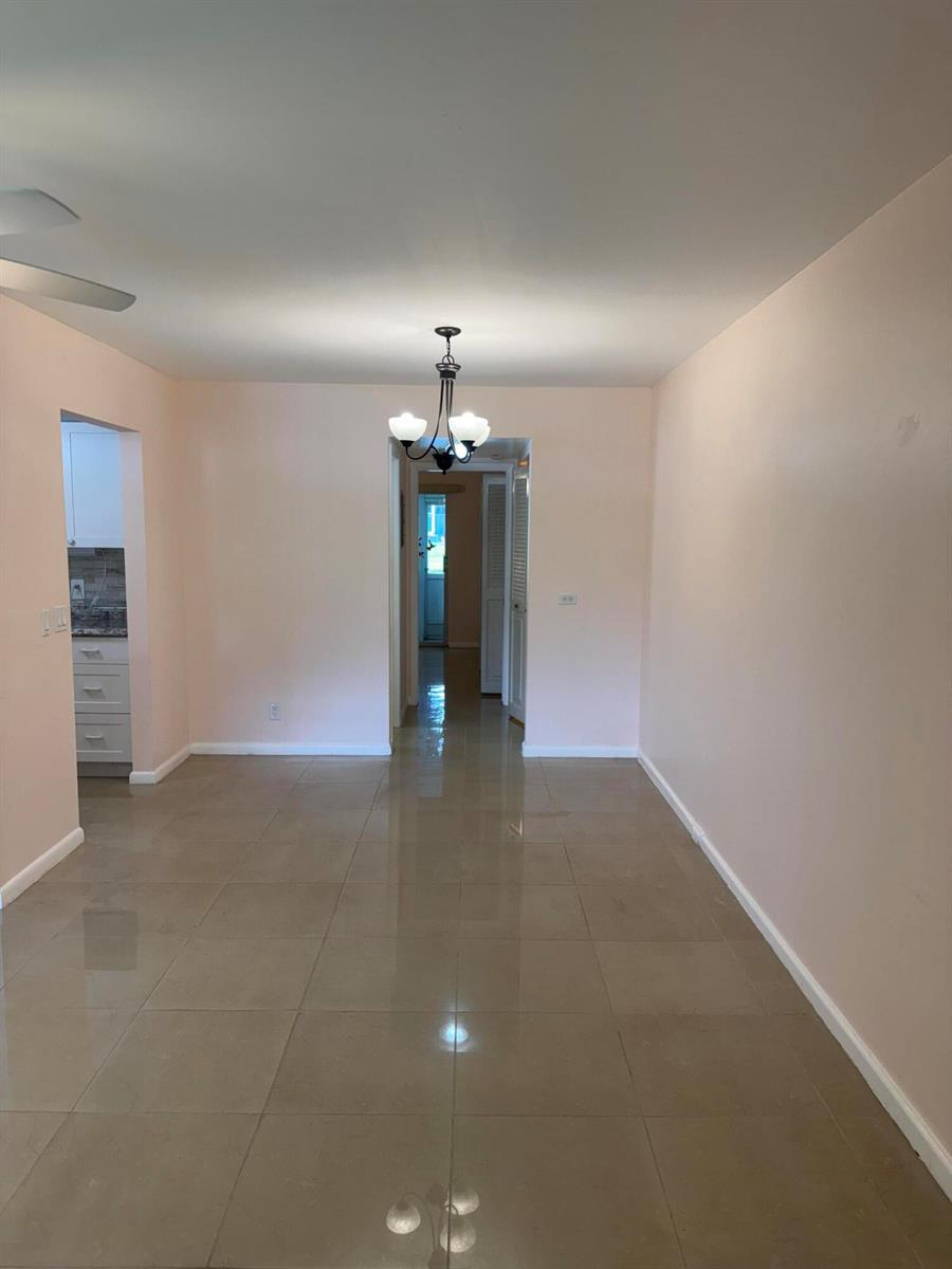 A dining area with light pink walls, large beige floor tiles, and a central chandelier — 463 Tilford V # 463, Deerfield Beach FL 33442, DEERFIELD BEACH, FL