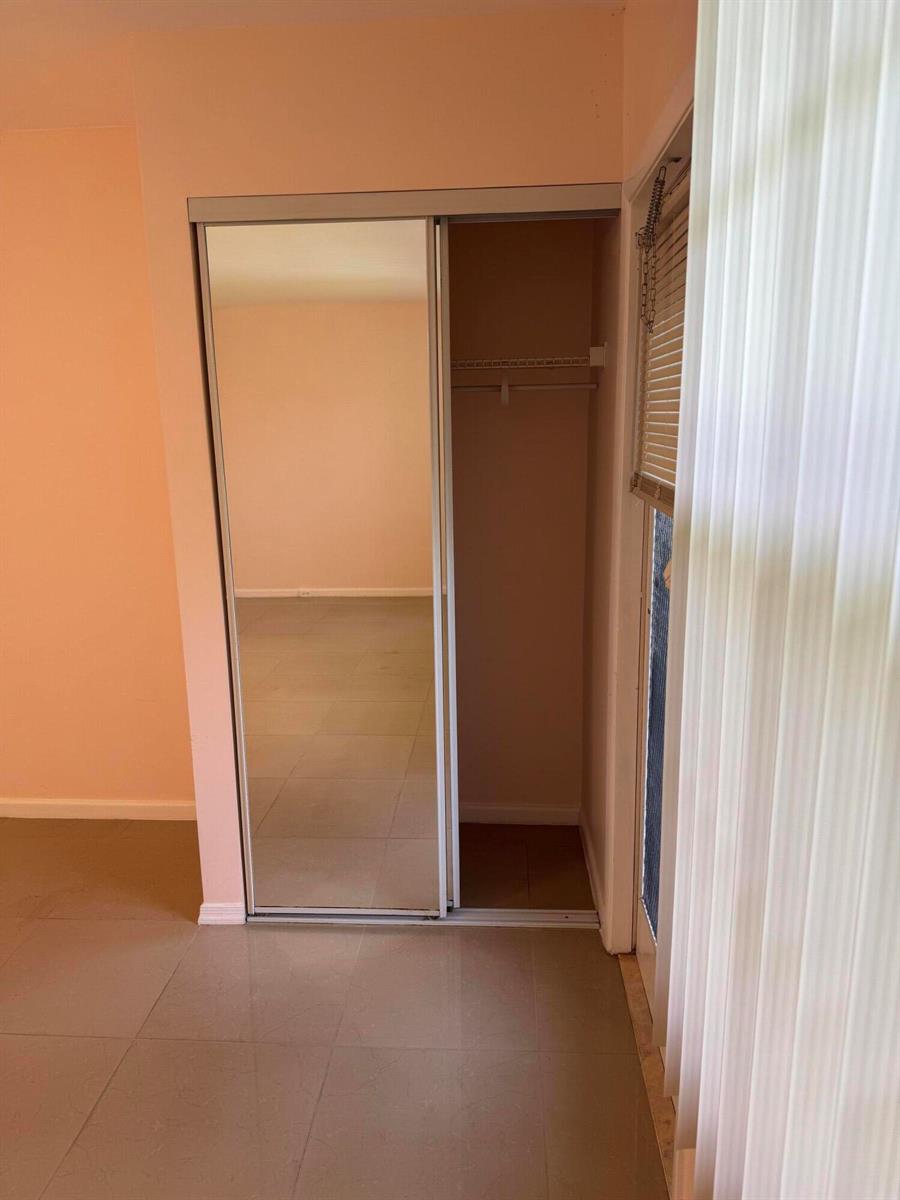 A room features a closet with a sliding mirrored door and light-colored tile flooring — 463 Tilford V # 463, Deerfield Beach FL 33442, DEERFIELD BEACH, FL