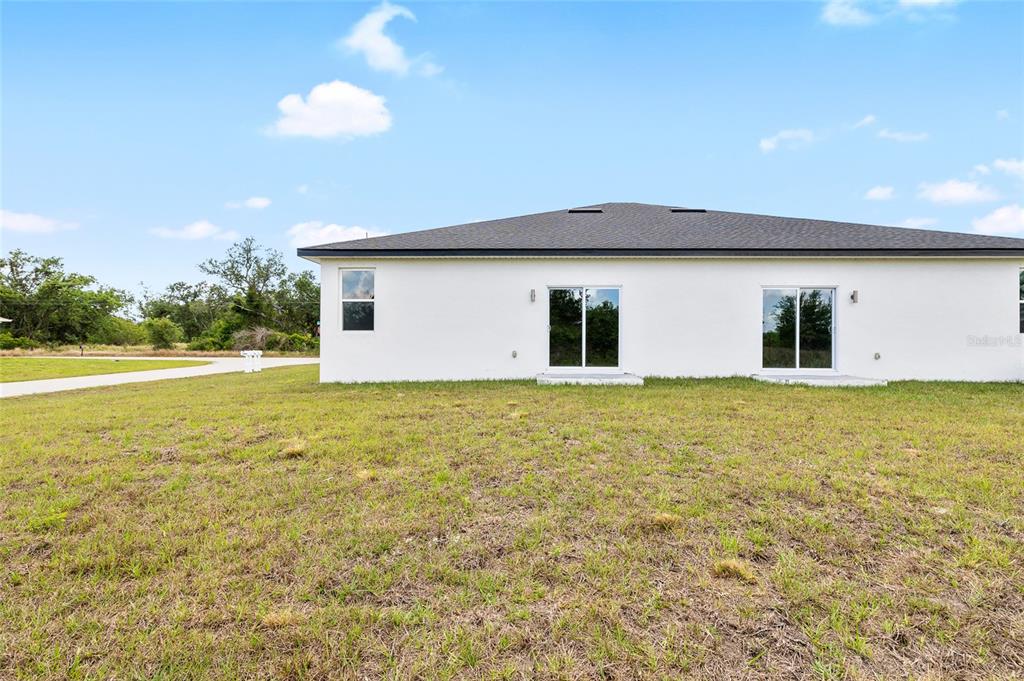 The exterior rear view of a white single-story house with two sliding glass doors — 10026 COCOA BEACH STREET, PORT CHARLOTTE, FL