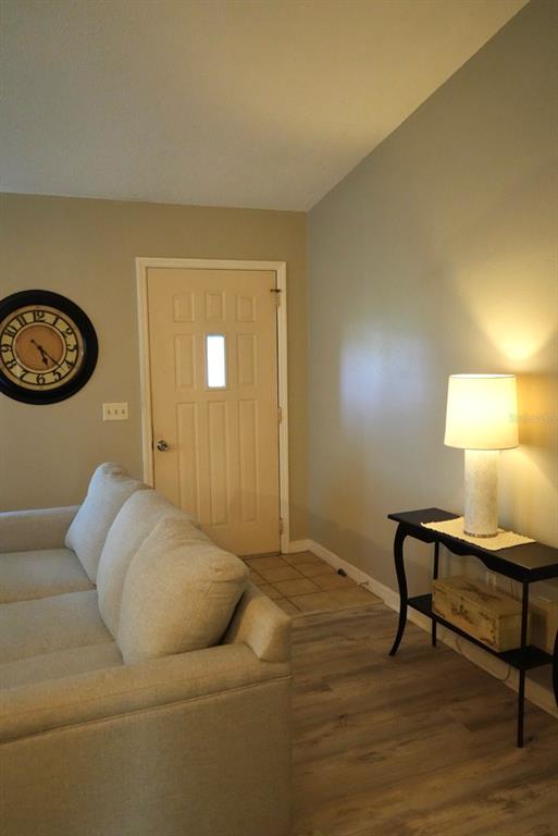 A living room features a light-colored sofa, a wall clock, and a console table — 10046 CHARLEMONT AVENUE, ENGLEWOOD, FL