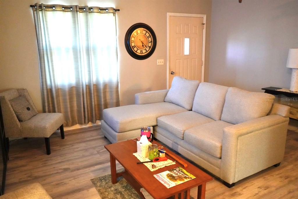A living room features a light gray sectional sofa, a wooden coffee table, and a clock — 10046 CHARLEMONT AVENUE, ENGLEWOOD, FL