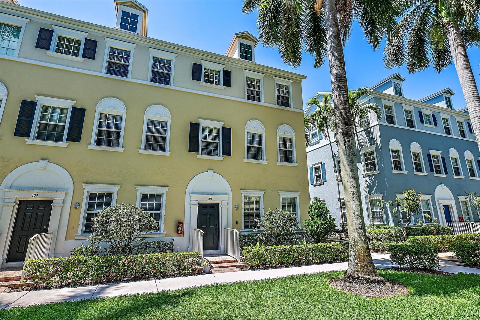 A yellow three-story townhouse with a dark door and a blue townhouse next door — 107 Pond Apple Lane # 105, Jupiter FL 33458, JUPITER, FL