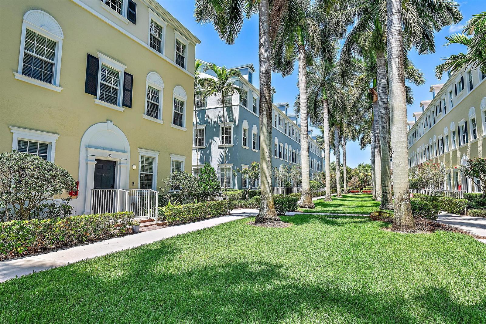 A grassy courtyard with palm trees sits between two rows of multi-story residential buildings — 107 Pond Apple Lane # 105, Jupiter FL 33458, JUPITER, FL