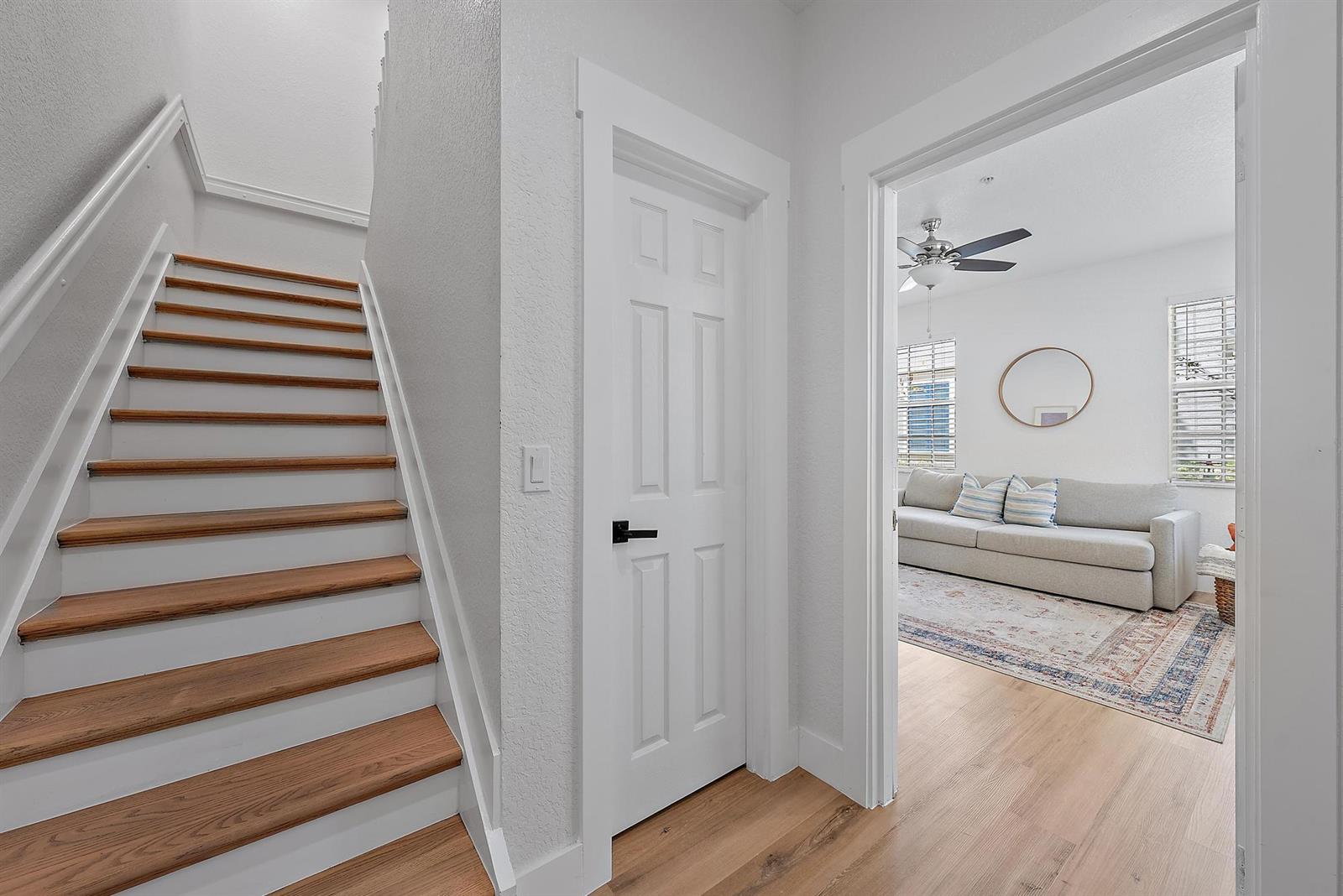 A wooden staircase stands beside a closed white door and an entryway to a living room — 107 Pond Apple Lane # 105, Jupiter FL 33458, JUPITER, FL