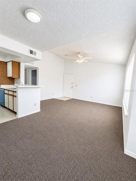 A living room with beige carpet, white walls, a ceiling fan, and an adjacent kitchen — 1033 S HIAWASSEE ROAD UNIT 2622, ORLANDO, FL