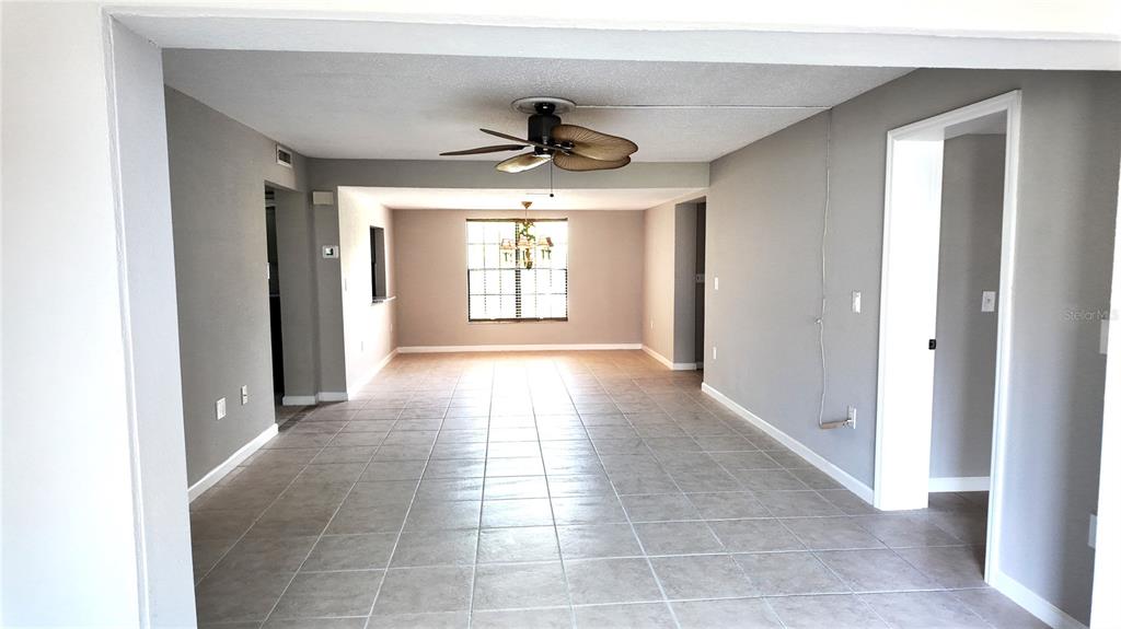 A spacious, empty room features light gray walls, tiled flooring, and a ceiling fan — 2480 PELICAN COURT UNIT 102R, CLEARWATER, FL