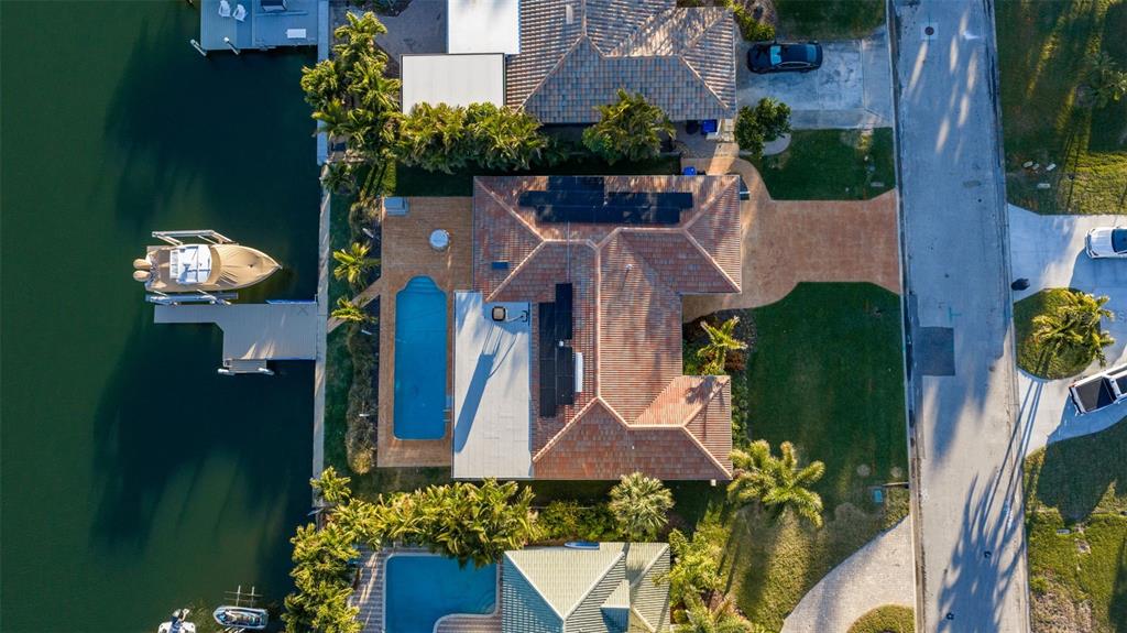 An aerial view shows a waterfront house with a pool, boat dock, and solar panels — 2024 MASSACHUSETTS AVENUE NE, ST PETERSBURG, FL