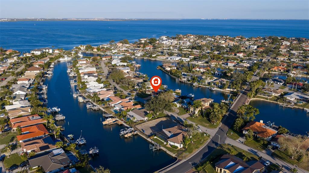 An aerial view shows a waterfront residential neighborhood with homes along canals and a bay — 2024 MASSACHUSETTS AVENUE NE, ST PETERSBURG, FL
