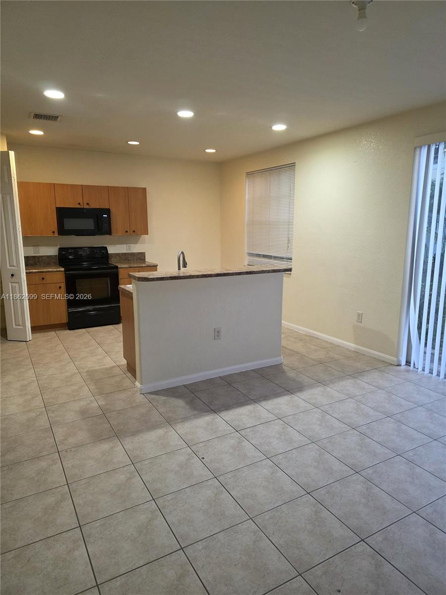 A kitchen features light wood cabinets, black appliances, a breakfast bar, and tiled flooring — 2584 SW 84th Ter # 101, Miramar FL 33025, MIRAMAR, FL