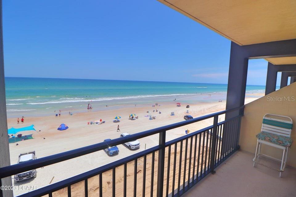A balcony overlooks a sandy beach with parked cars and the ocean — 2301 S ATLANTIC AVENUE UNIT 438, DAYTONA BEACH, FL