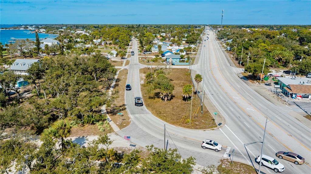 An aerial view shows a coastal road intersection with surrounding trees, buildings, and moving vehicles — 800 S MCCALL ROAD, ENGLEWOOD, FL
