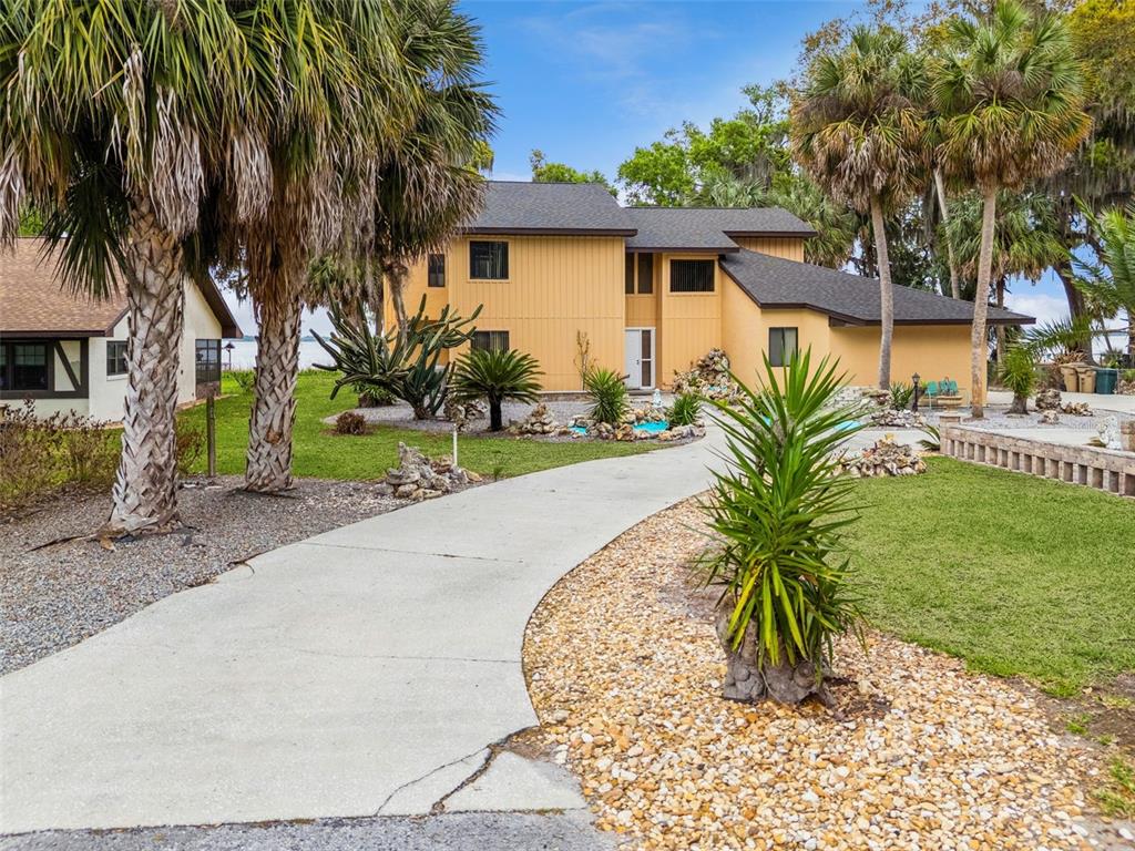 A two-story yellow house with a concrete walkway and palm trees in the front yard — 35312 W GRIFFIN DRIVE, FRUITLAND PARK, FL