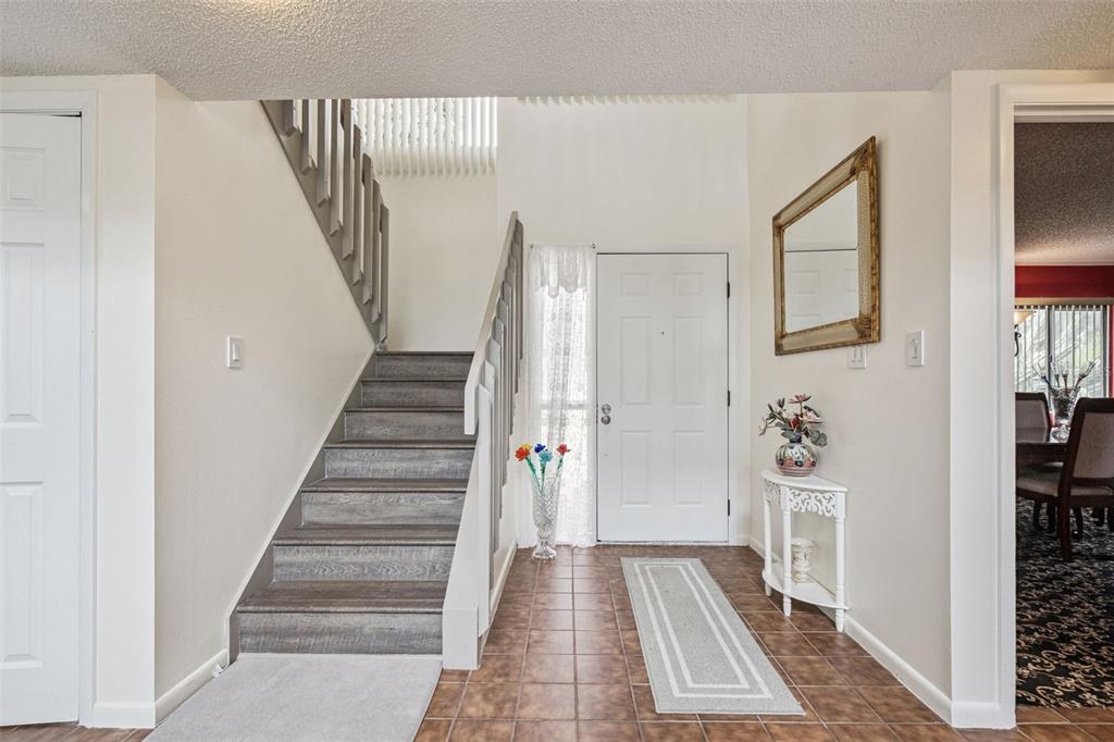 An entryway features a staircase with wood-look treads, tiled flooring, and a white front door — 35312 W GRIFFIN DRIVE, FRUITLAND PARK, FL