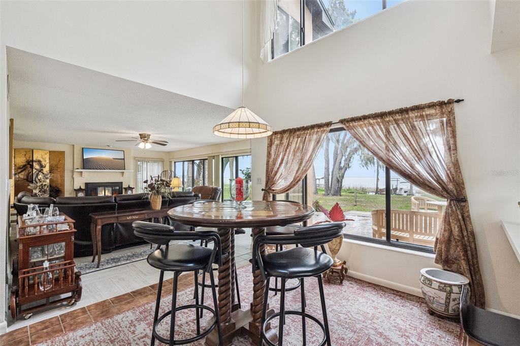 A dining area with a high ceiling overlooks a living room and a waterfront view — 35312 W GRIFFIN DRIVE, FRUITLAND PARK, FL
