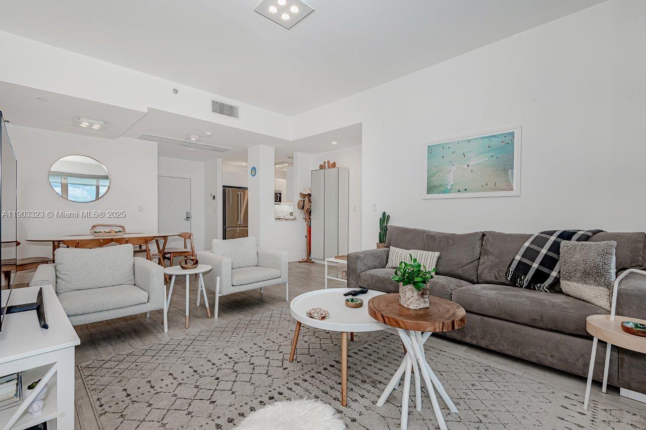 A living room features a gray sofa, two light-colored armchairs, and a patterned area rug — 2301 Collins Ave, Miami Beach FL 33139, MIAMI BEACH, FL
