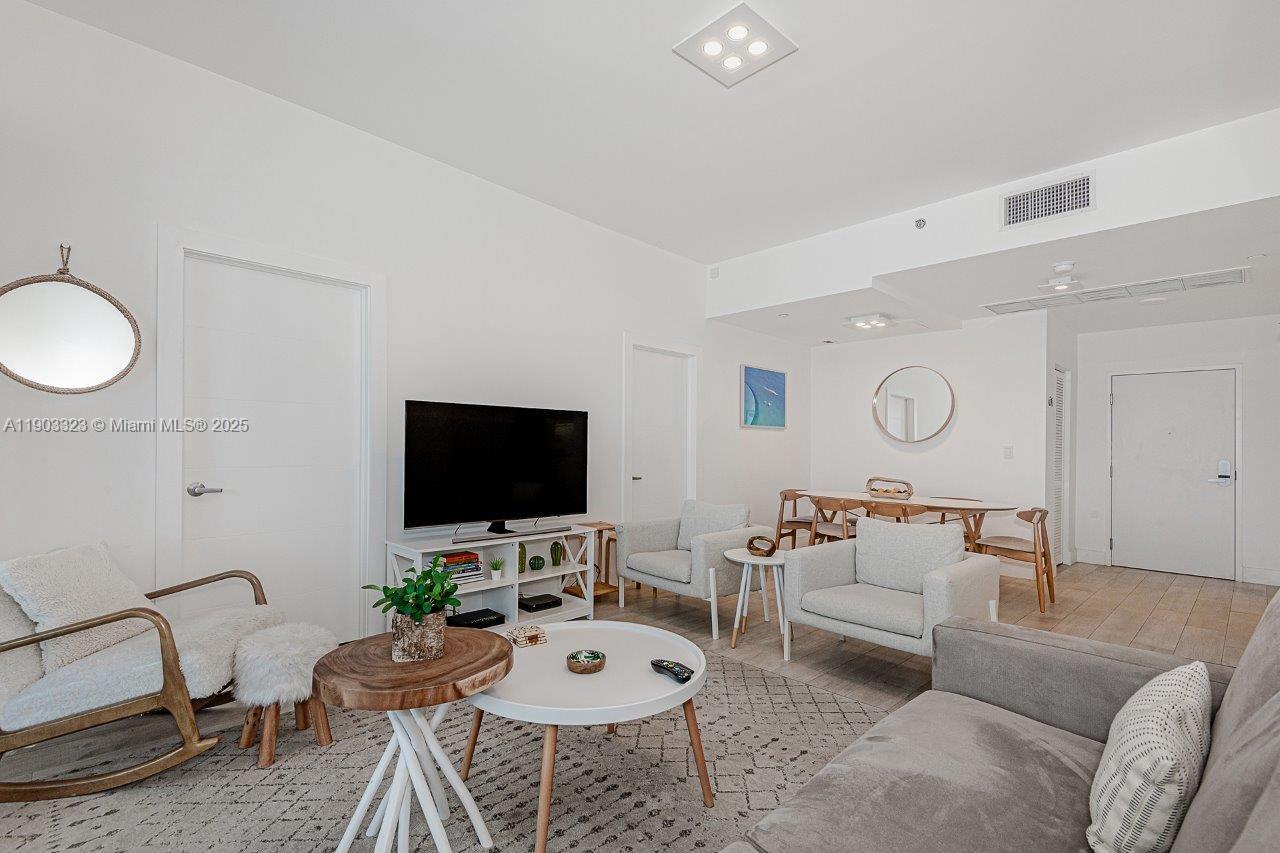 A living room features a television, white furniture, a wooden coffee table, and dining area — 2301 Collins Ave, Miami Beach FL 33139, MIAMI BEACH, FL